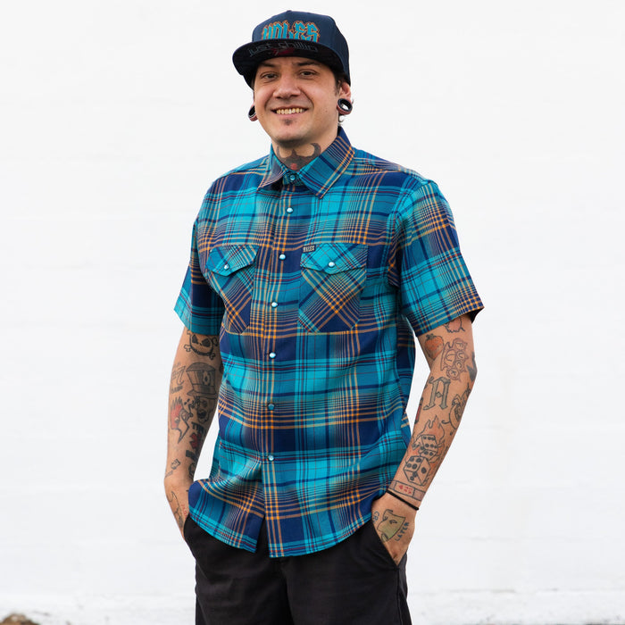 Man wearing a blue plaid shirt and cap on a white background